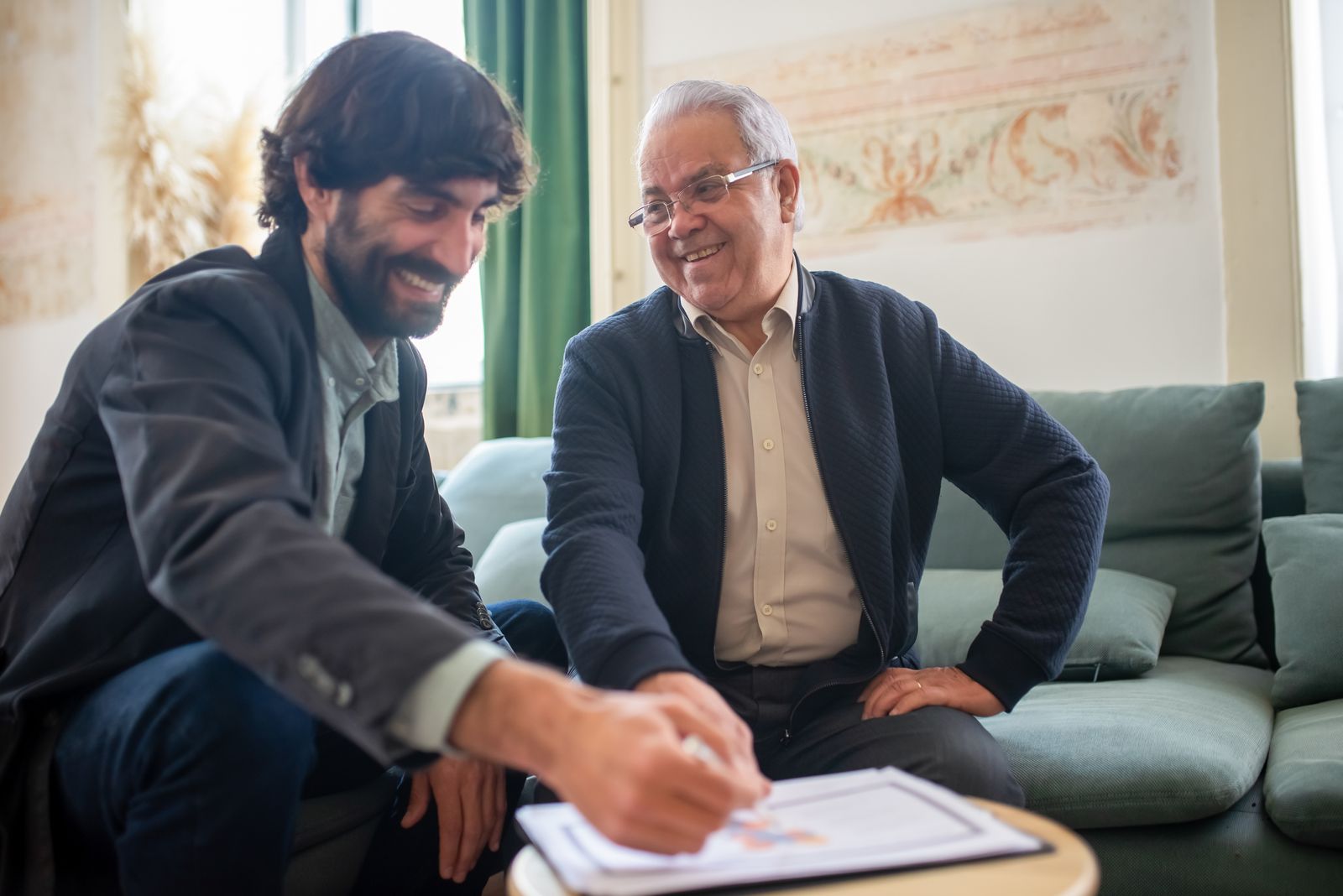 Un consulente spiega un documento a un signore anziano seduto sul divano