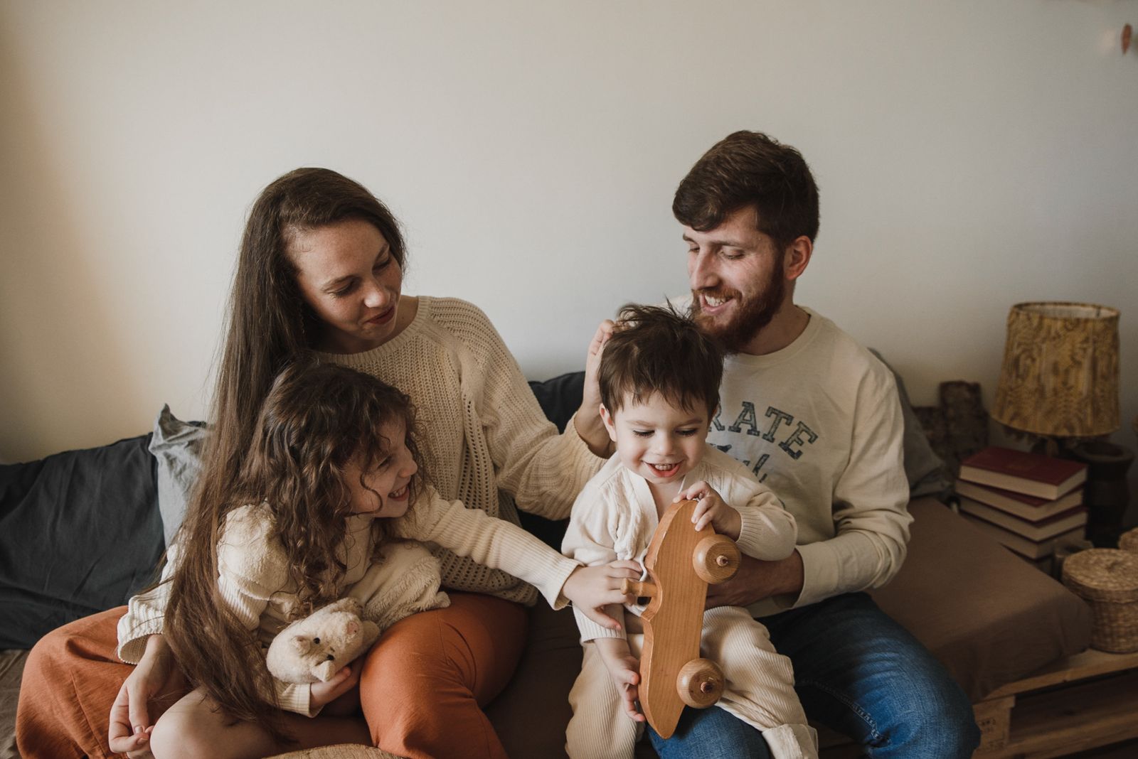 Una famiglia con due bambini piccoli seduta insieme sul divano di casa