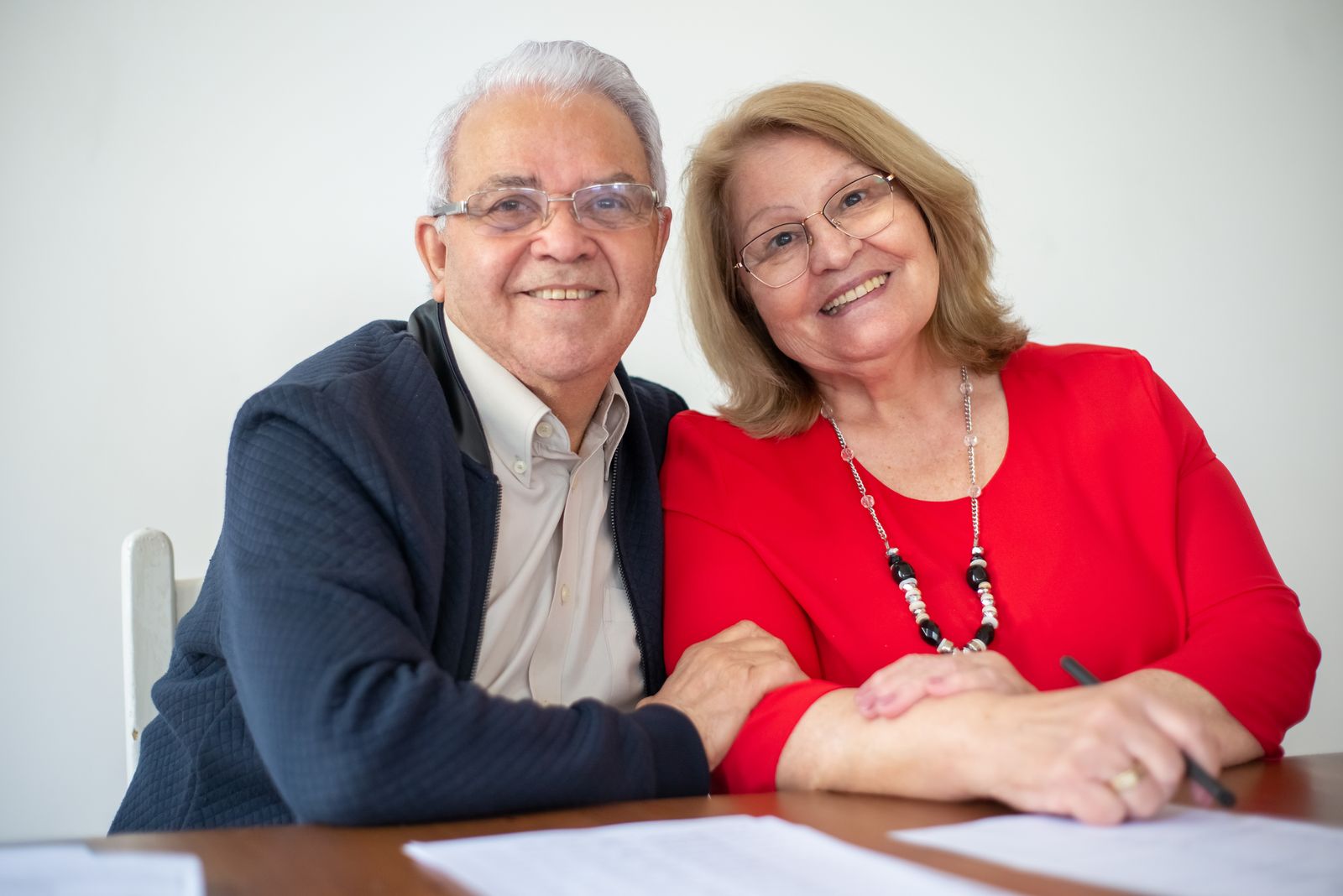 Una coppia di pensionati sorridente mentre firma dei documenti alla scrivania