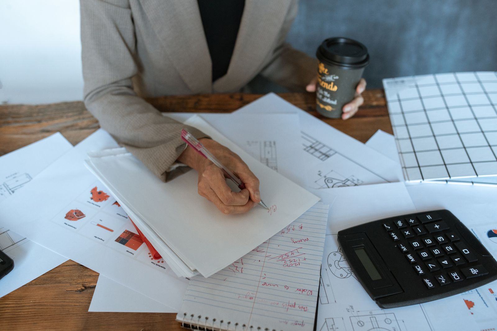 Una professionista al lavoro su dei fogli con la calcolatrice